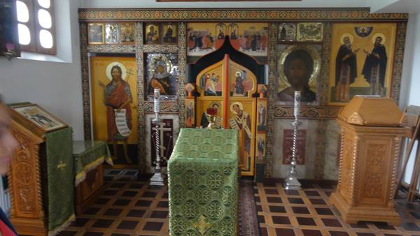 Golden iconostasis with icons and green-covered altar inside an Orthodox church