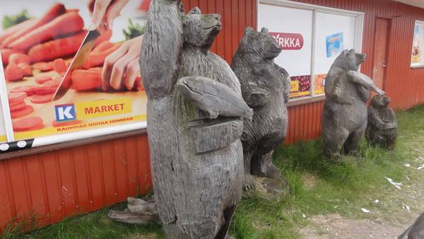 Wooden bear sculptures holding fish outside a market
