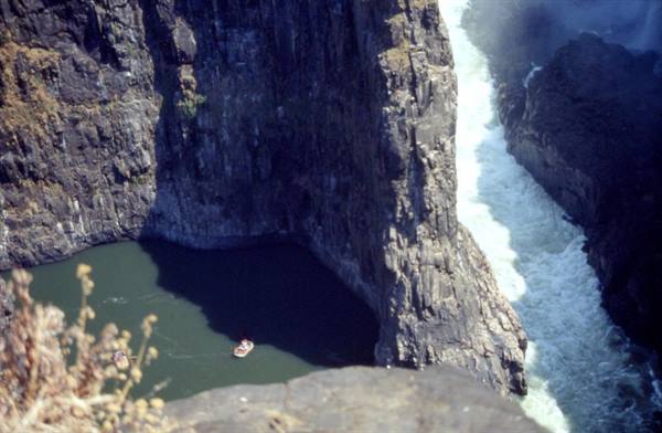 Raft on green water beneath basalt gorge walls, Zambezi River rapids