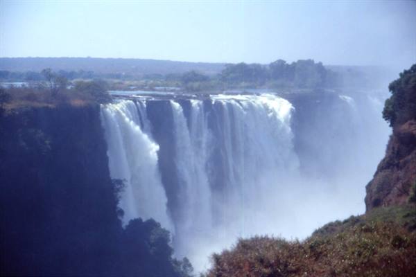 Victoria Falls, massive waterfalls pouring over cliffs with rising mist