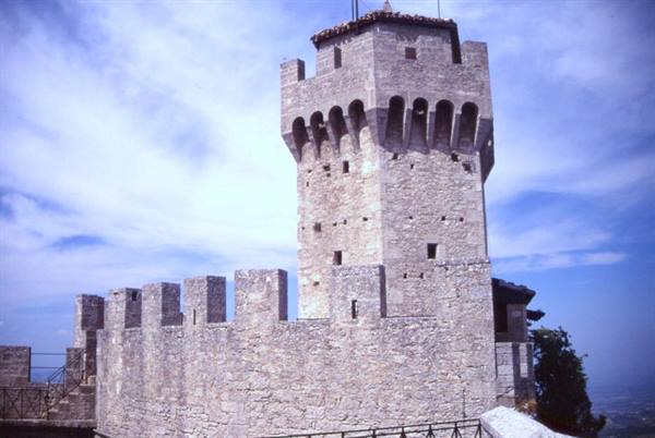 Stone crenellated tower with walls under cloudy sky, San Marino