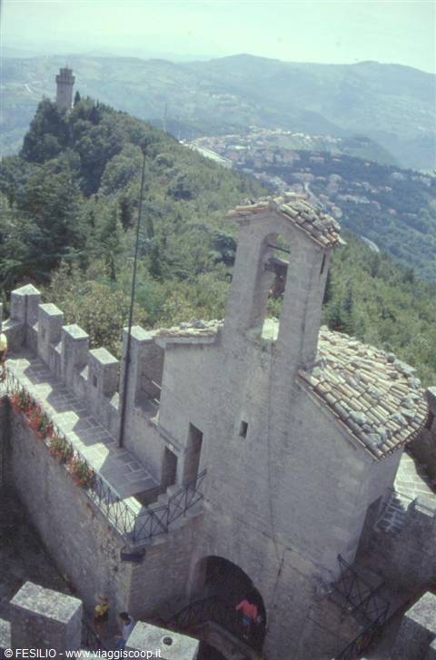 Stone tower of San Marino with battlements, green hills and second tower on the hill