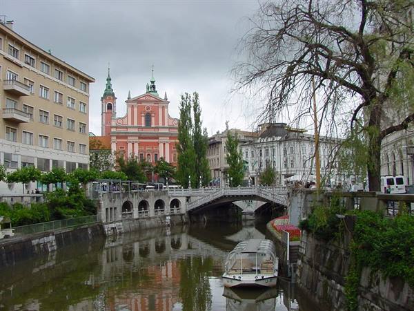 Ljubljana: pink Franciscan church, stone bridge and boat on the river