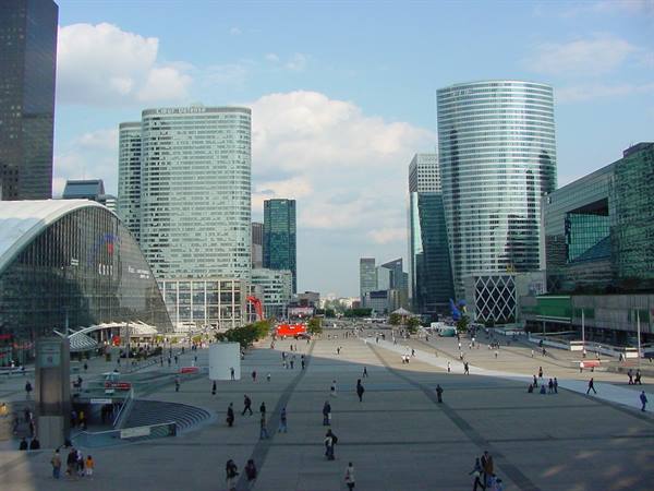 La Défense plaza in Paris, glass skyscrapers and pedestrians under white clouds