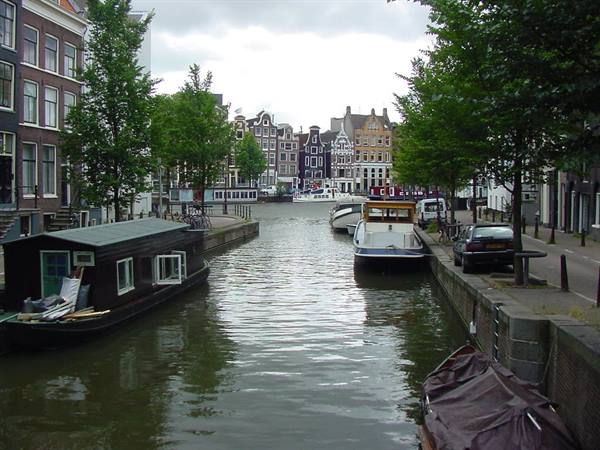 Amsterdam canal with gabled houses, dark houseboat and moored boats