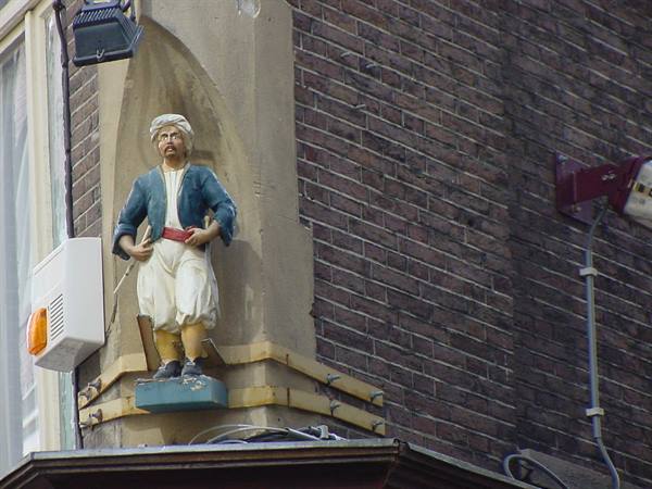 Statue of a man in turban and blue jacket set into brick corner