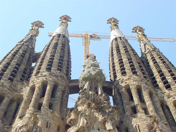 Towering spires of the Sagrada Família in Barcelona against blue sky, cranes