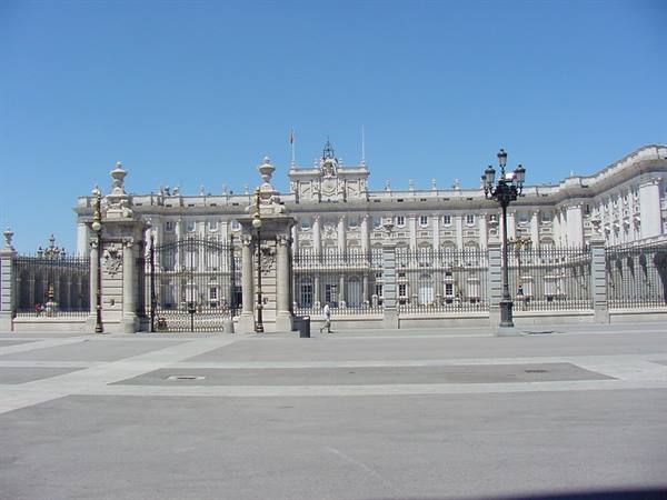 Royal Palace of Madrid, stone facade behind wrought iron gates under blue sky