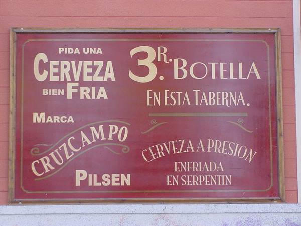 Painted red tavern sign advertising Cruzcampo Pilsen beer, three pesetas a bottle
