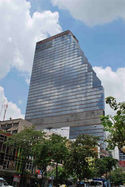 Reflective glass skyscraper rising above street trees and traffic