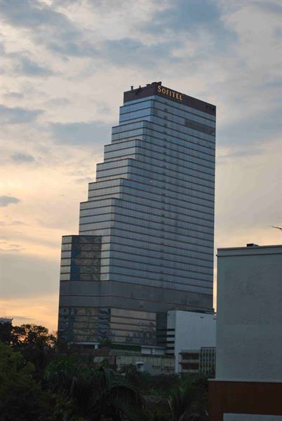 Glass skyscraper with Sofitel sign rising into cloudy sky