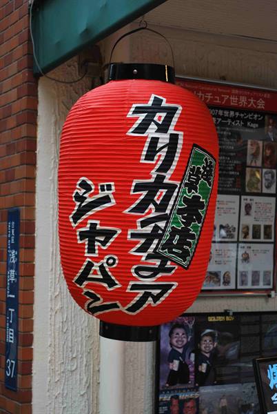 Red paper lantern with black characters hanging outside a Japanese restaurant