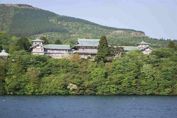 Hakone Shrine nestled among trees above Lake Ashi, green mountain behind
