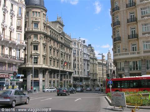 Elegant buildings on Gran Vía, Madrid, red bus and cars in the sun