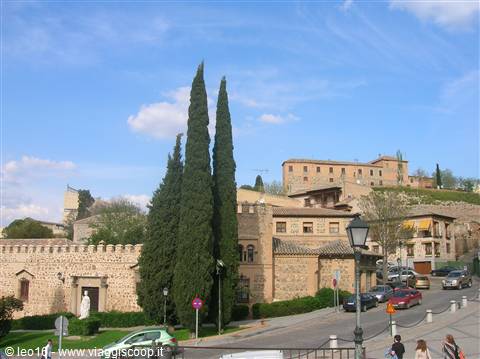 Crenellated walls and tall cypresses along the road in Toledo