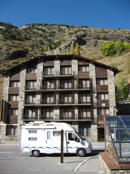 White motorhome parked in front of a stone and wood mountain hotel