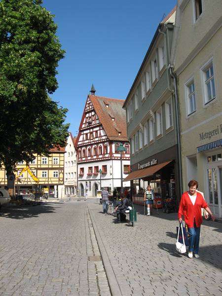 Woman in red walks on cobblestone street past half-timbered houses