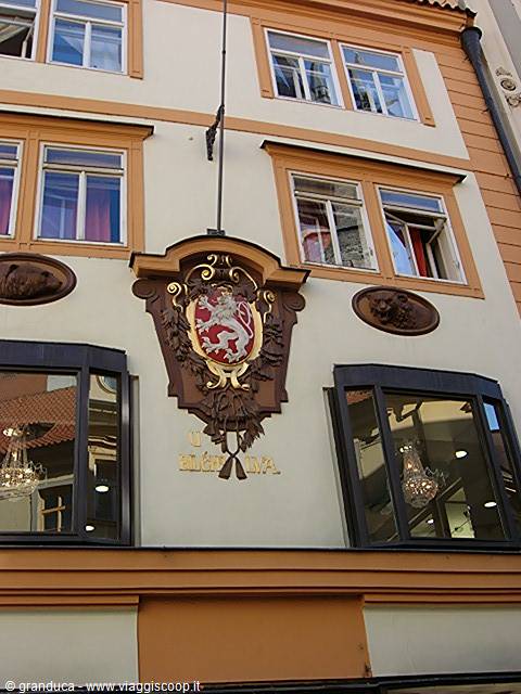 Peach facade with red lion crest between two shop windows