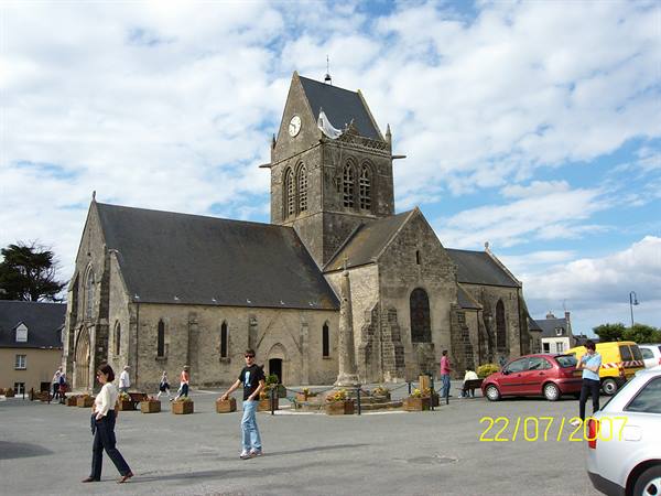 Sainte-Mère-Église church, parachute on the bell tower, tourists on the square