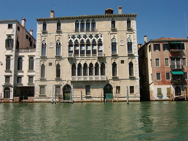 Gothic palace on Venice's Grand Canal, marble facade, green water under bright sun