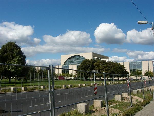 Chancellery building in Berlin behind construction fence under cloudy sky