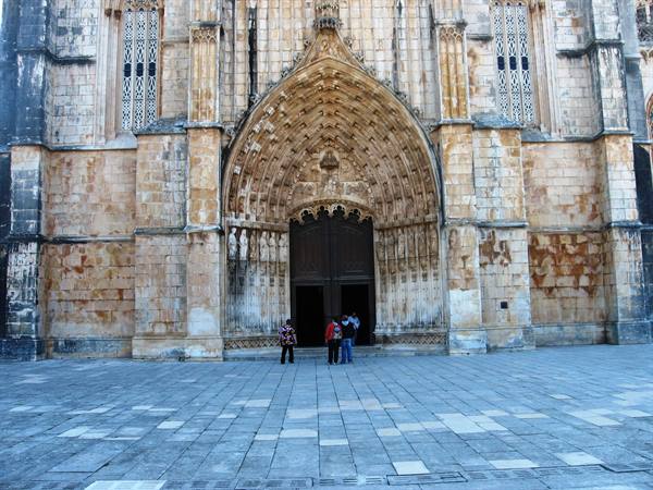 Tourists before the Gothic stone portal of Batalha Monastery