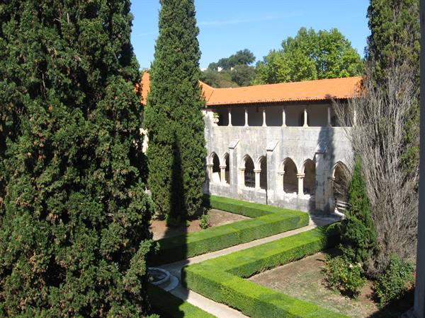 Gothic cloister of Batalha Monastery with boxwood garden and cypress trees
