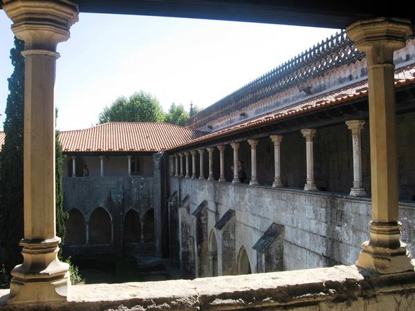 Medieval stone cloister with columns and red-tiled roofs