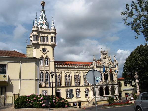 Sintra town hall with ornate tower, cloudy sky, flags and hydrangeas