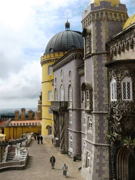 Visitors stroll in the Pena Palace courtyard, yellow domes and tiles above