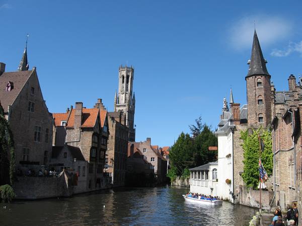Tourist boat on a Bruges canal, brick houses and the Belfry tower