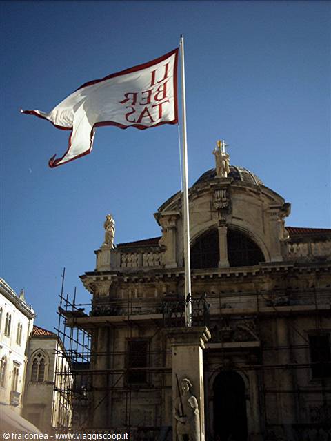 Libertas flag on a pole in front of Dubrovnik's Saint Blaise Church
