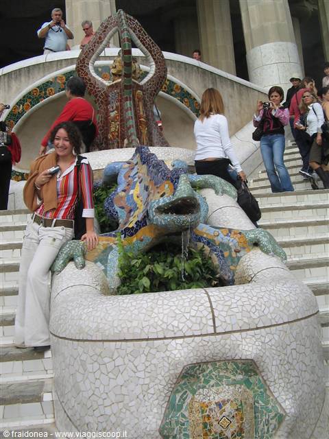 Tourist posing next to Gaudí's mosaic salamander at Park Güell, Barcelona