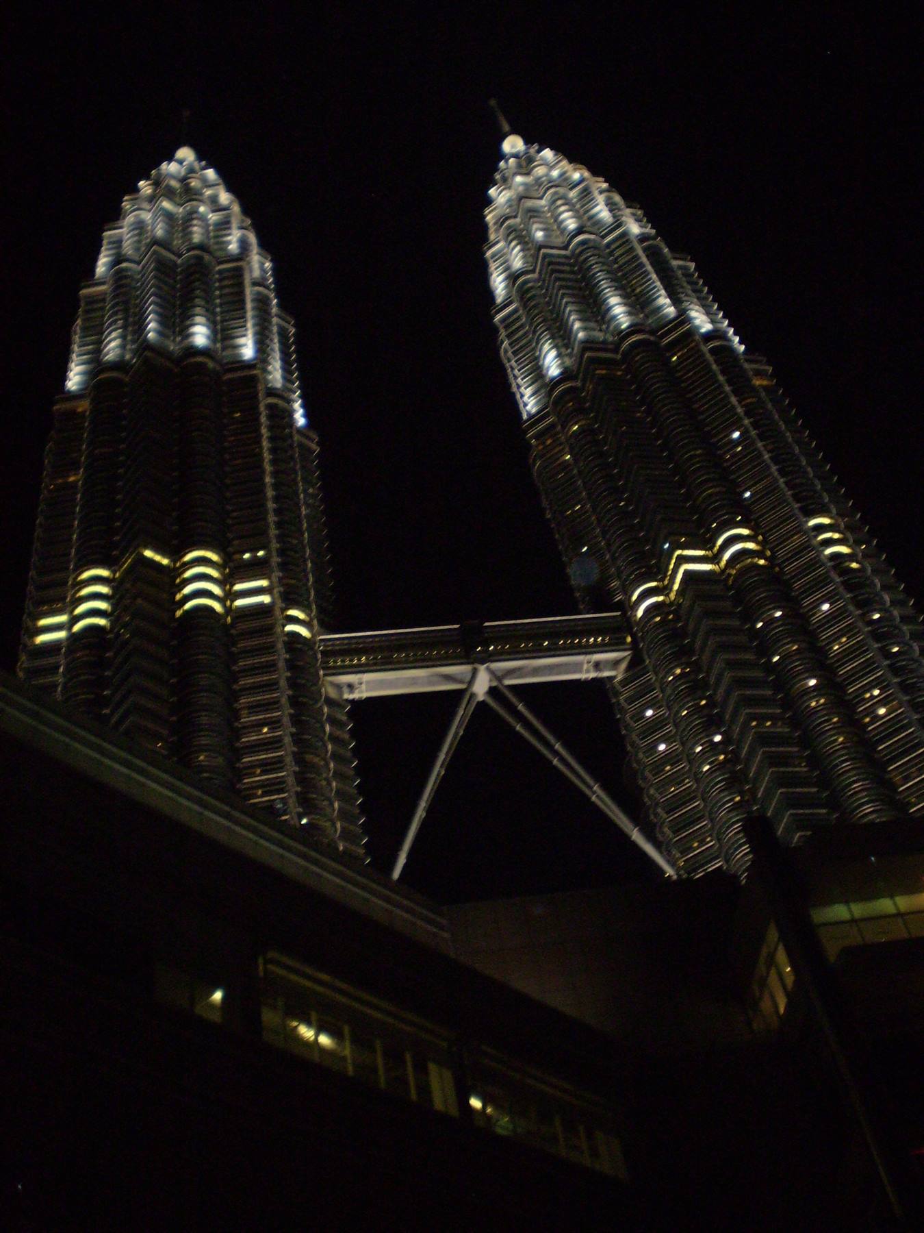 The illuminated Petronas Towers at night in Kuala Lumpur, with skybridge