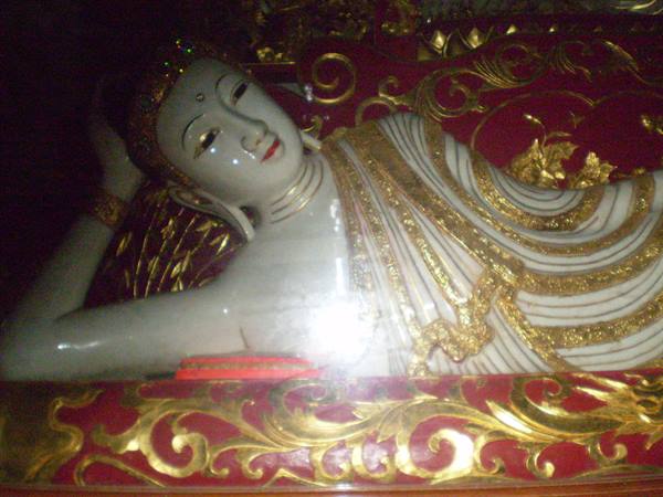 Reclining Buddha in white marble and gold, red robes, soft indoor light