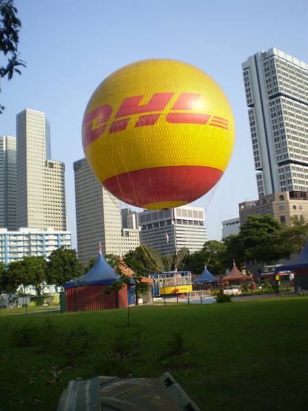 Yellow DHL balloon floats above green park with skyscrapers
