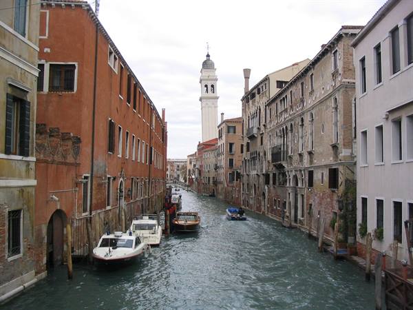 Motorboat cruising a Venice canal between old palaces and a bell tower