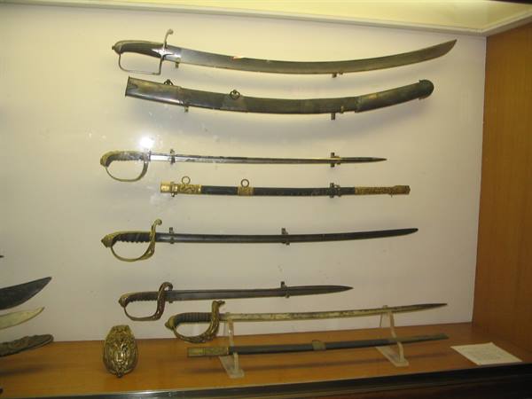 Historic sabers displayed on white wall in museum showcase