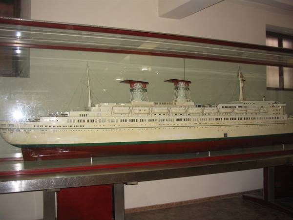 Model of a white ocean liner with two red funnels in a glass case