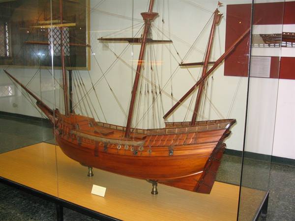 Wooden model of a three-masted ship displayed in a museum glass case