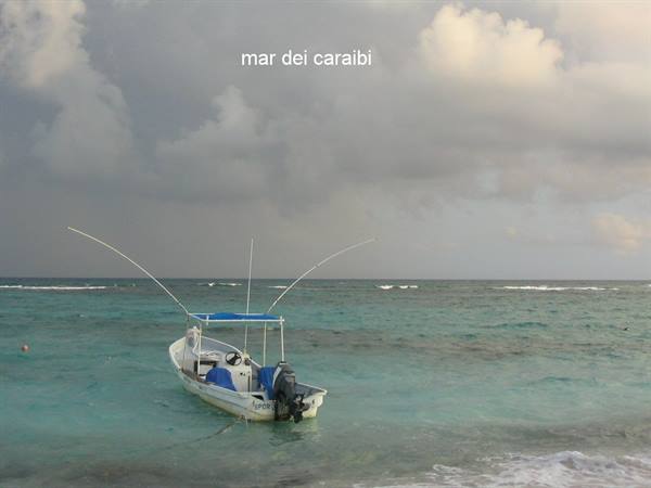White fishing boat anchored among turquoise waves, cloudy sky over the Caribbean