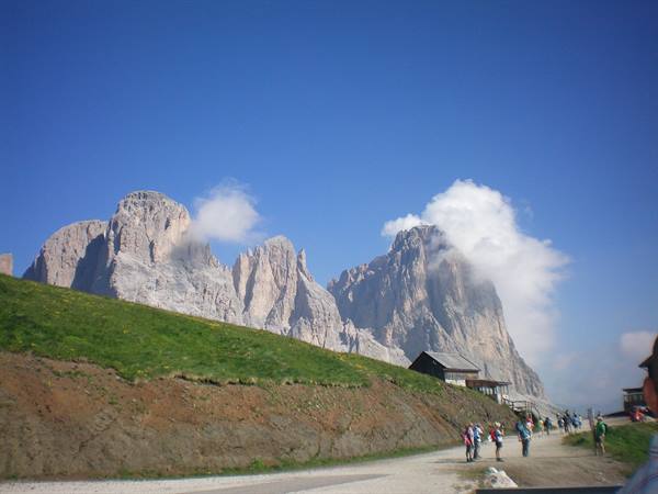 Hikers on a trail beneath the dolomite peaks of Sella