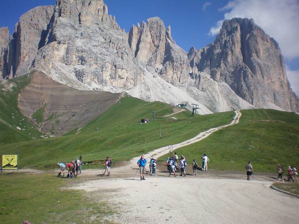 Hikers on the grassy trail beneath the SellaGroup dolomite peaks