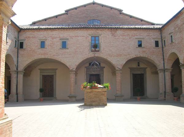 Brick Renaissance cloister with arched porticoes and flowered central well