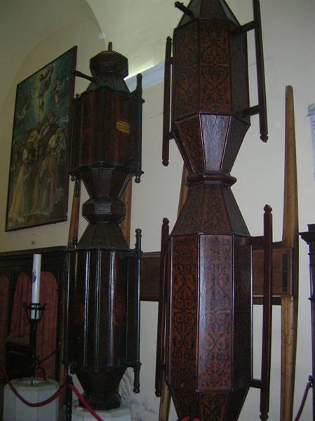 Large carved wooden processional lanterns displayed inside a church