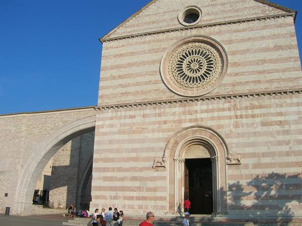White and pink stone facade of Santa Chiara Basilica in Assisi with rose window
