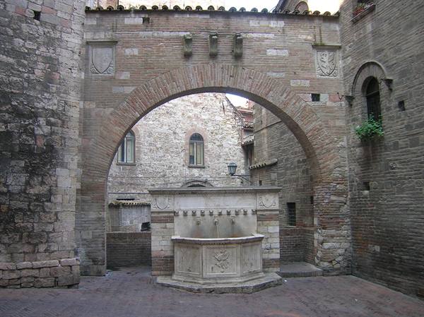 Medieval stone fountain beneath a brick arch, Perugia