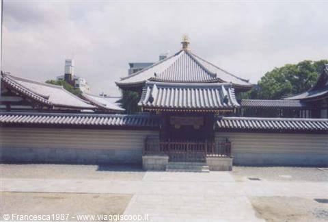 Buddhist temple with grey tiled roofs and white walls under cloudy sky
