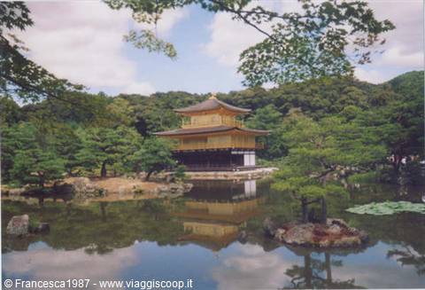Golden Kinkaku-ji pavilion reflected in pond, trees framing the scene