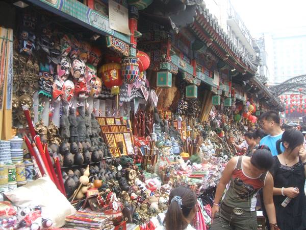 Shoppers browse masks and souvenirs under ornate roofs at Wangfujing street market